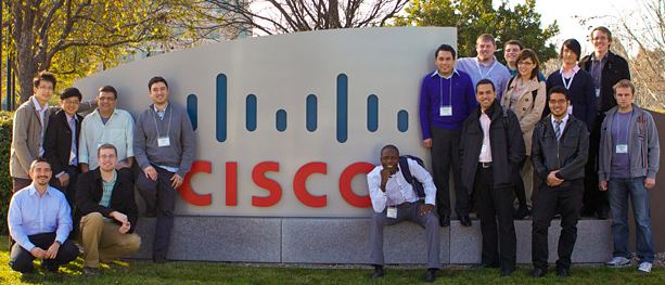 équipe de technicien CISCO devant une affiche géante CISCO