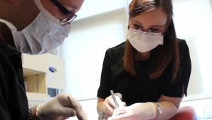 Soins dentaires - une assistante dentaire administre des soins à une patiente avec le dentiste à coté